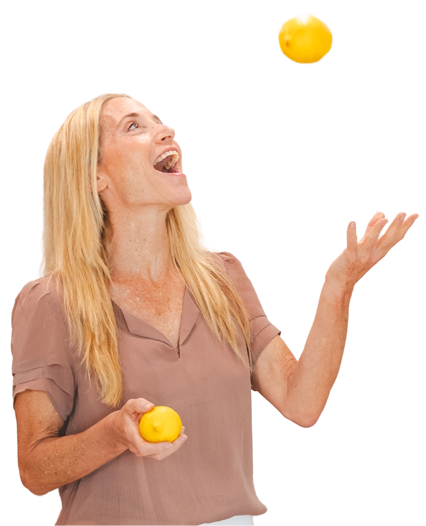 Leslie Crisco laughing while tossing a lemon in the air and holding another lemon in the other hand.