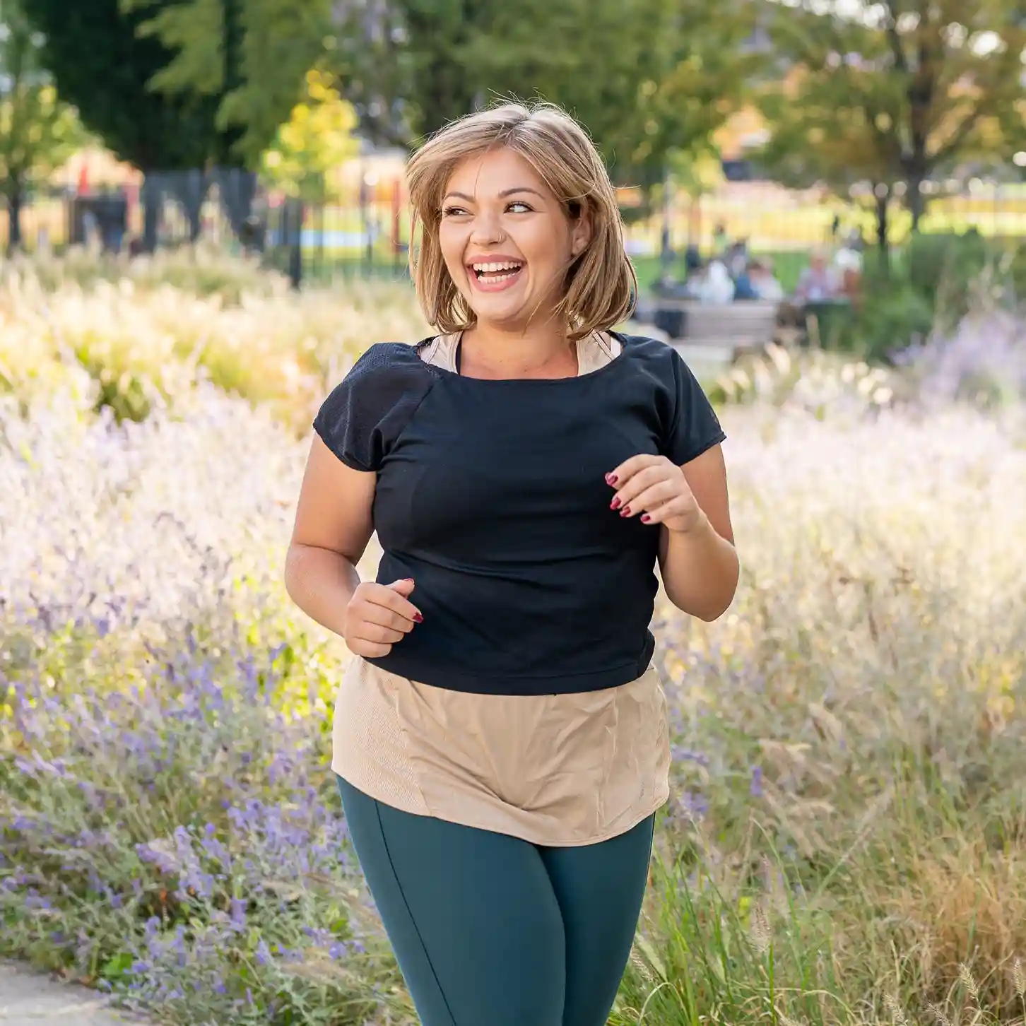 Woman smiling during a jog at a park during the day.
